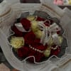 A bouquet of red and white roses, adorned with pearls and lace