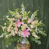 A pastel urn  arrangement using white snapdragons,pale yellow stock,pink lily,and soft
