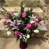 A lavender colored bouquet of flowers in a purple vase. Perfect for