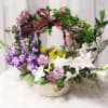 A basket of mixed blooms topped off with a handle of fragrant