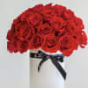 Classic red roses arranged in white ceramic vase. Our signature black ribbon