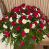 This casket spray features red roses with white carnations that drape over