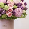 The arrangement includes the following flowers; peonies, lilacs, spray roses and hydrangea.