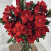 This elegant floral arrangement features a lavish bouquet of vibrant red roses