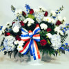Red roses, white carnations, blue delphinium, blue hydrangeas and white daisies designed