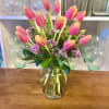 20 stems of orange tulips with wax flower and greens in a