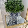 An artificial topiary ball in a classic blue and white ceramic pot