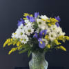A mint green vase full of daisies and blue iris.