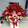 floral arrangement with 50 red roses, gerberas, spray roses, and green leaves.