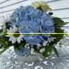 Blue hydrangea, white roses, white daisys in a white ceramic 