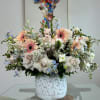 Garden-style arrangement featuring blush roses, peach gerbera daisies, delicate delphiniums, and lush