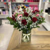 Assorted bouquet with red roses, ran&uacute;nculos, mini calla lilies, and green leaves.