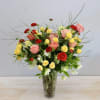 This arrangement is filled with vibrant red ranunculus, yellow spray roses, peach