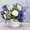 This dreamy arrangement brings together white dahlias and blue delphiniums with spray