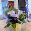 This elegant centerpiece features rich shades of purple&mdash;chrysanthemums, stock, poms, and carnations&mdash;arranged