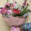 A romantic floral arrangement featyring pink roses, peonies,carnationsmand wildflowers, accented with delicate