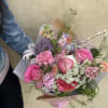 A romantic floral arrangement featyring pink roses, peonies,carnationsmand wildflowers, accented with delicate