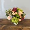 Petite compote arrangement in cream colored vase. Includes peach, pink, purple, and