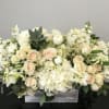 All white hydrangeas, roses, stock, and seasonals carefully arranged in a birchwood