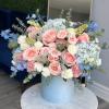 This arrangement features a stunning blend of lush blue hydrangeas, soft peach