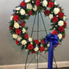 Large circular standing wreath, featuring red, white and blue flowers. A moving
