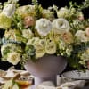 A lush and whimsical garden-style floral arrangement in a vase, brimming with