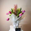 Twenty tulips arranged with care in a glass vase, softly wrapped in
