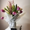 Twenty tulips arranged with care in a glass vase, softly wrapped in