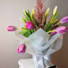 Twenty tulips arranged with care in a glass vase, softly wrapped in