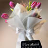 Twenty tulips arranged with care in a glass vase, softly wrapped in