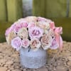 A delicate arrangement of pale pink and cream roses in a textured