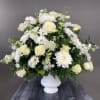 Round floral arrangement, on a white base, with roses, chrysanthemums, daisies, and