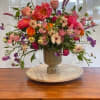 A full floral arrangement consists of beautiful blooms in a pottery vase
One-sided