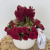 Arrangement features deep crimson roses and rich burgundy blooms in a textured