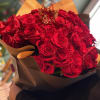 A luxurious red rose bouquet , hand wrapped with black silk paper