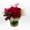 This arrangement showcases a charming bouquet featuring vibrant red roses, surrounded by