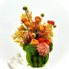 This floral arrangement features a delightful mix of vibrant flowers in warm