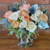 A lovely tabletop fresh flower arrangement with coral roses, blue thistle, Dusty