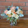 A lovely tabletop fresh flower arrangement with coral roses, blue thistle, Dusty