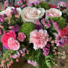 A green basket with a pop of hot pink roses, this arrangement