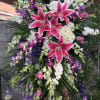 A graceful funeral easel spray featuring pink lilies, purple larkspur, fragrant stock