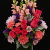 A vibrant and cheerful arrangement featuring hot pink roses, orange carnations, soft