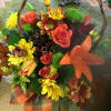 A basket arrangement with roses, lilies and fall daisies, for a colorful