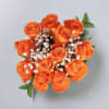 A dozen orange roses with greens and filler flower wrapped in a