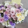 This is an elegant floral arrangement in soft pastel tones, presented in