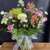 A bright display featuring, spray roses, mini carnations, buttons, hypericum berries and
