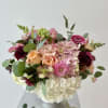 A lovely flower centerpiece in a compote vase with premium flowers the