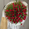large bouquet of red tulips in white packaging with ribbon