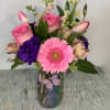 Arrangement of mixed flowers designed in a pastel color iridescent vase. Vase
