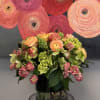 Ranunculus, hydrangea, hyacinth,spray roses, helebores in a clear glass vase.